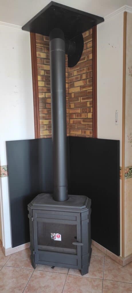 Poêle à bois avec conduit de fumée intérieur et plaque de protection murale – installation conforme