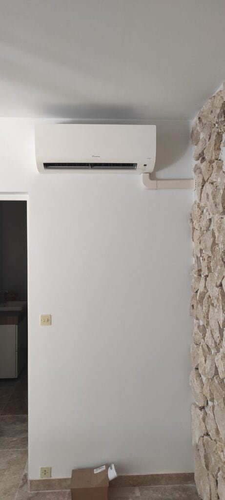 Unité intérieure de climatisation Daikin dans une pièce avec mur en pierre apparente