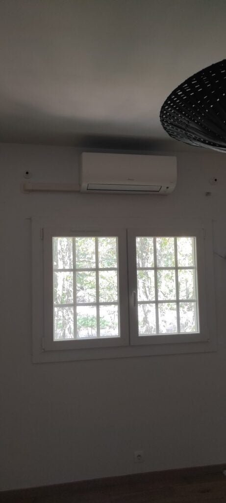 Unité intérieure murale Daikin installée au-dessus de la fenêtre d'une chambre