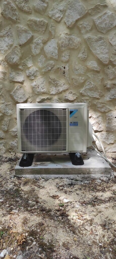 Groupe extérieur de climatisation Daikin Multi Inverter R32 sur plots anti-vibratiles contre un mur en pierre