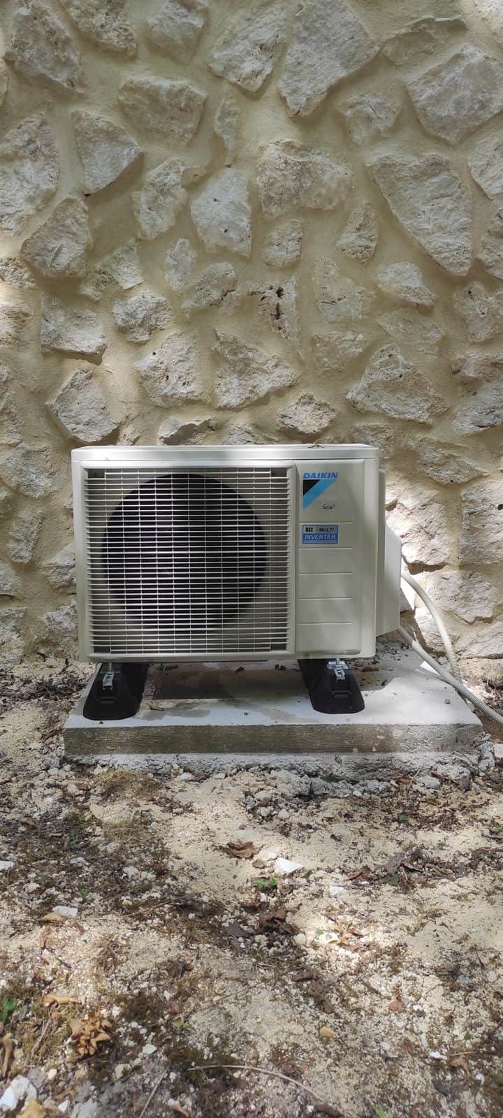 Groupe extérieur de climatisation Daikin Multi Inverter R32 sur plots anti-vibratiles contre un mur en pierre